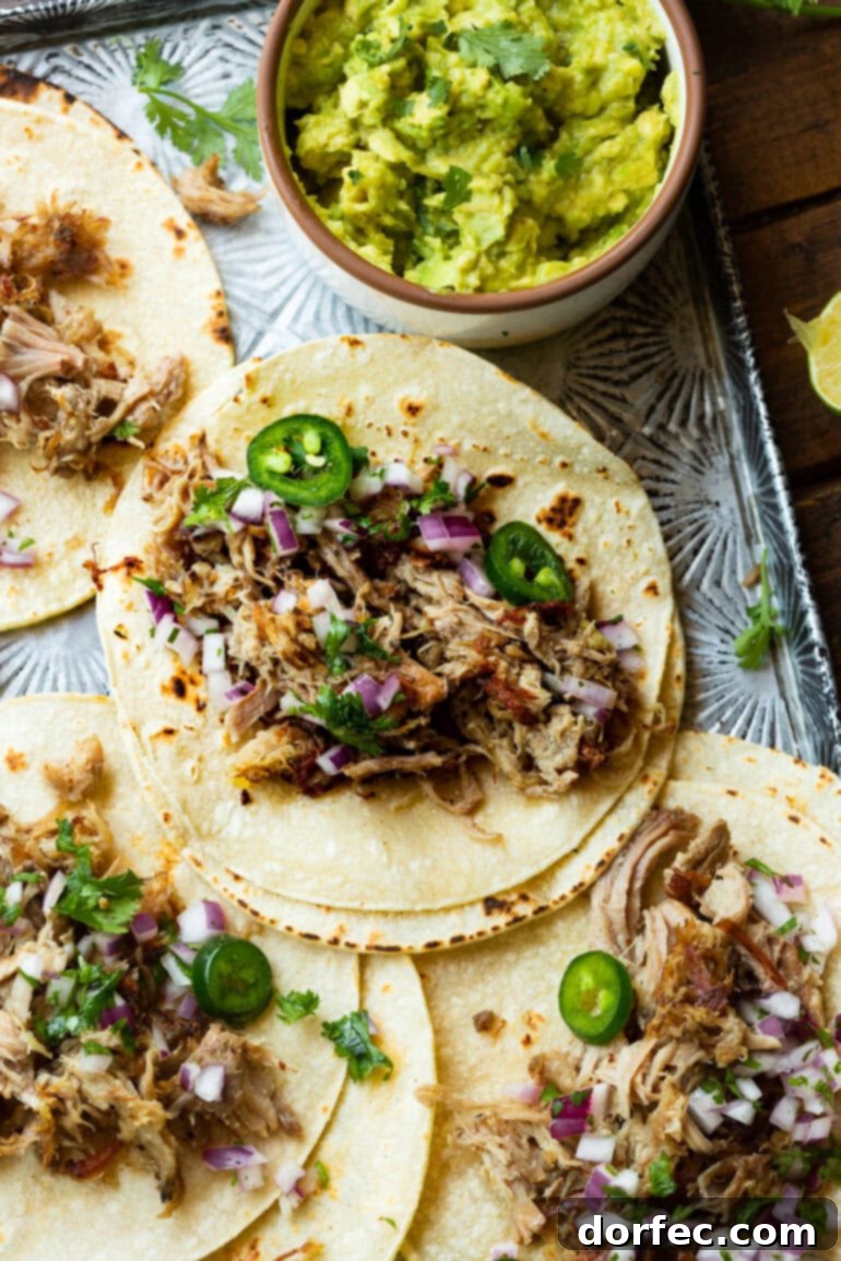 A visually appealing platter of several open flour tortillas, each laden with succulent pork carnitas, bright sliced jalapeños, crisp chopped red onion, and fresh cilantro, showcasing a vibrant and delicious meal spread. Keywords: carnitas serving ideas, Mexican food spread, easy weeknight meal