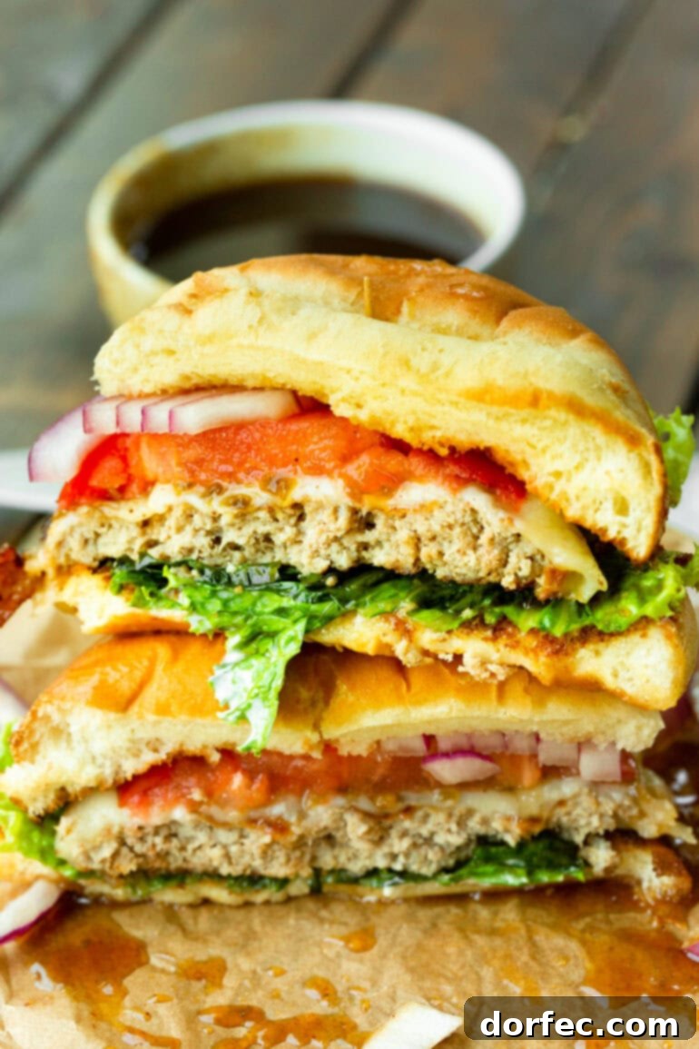 A vibrant pineapple jalapeno turkey burger sliced in half, showcasing the tender turkey patty, melted Havarti cheese, fresh lettuce, red onion, and tomato, all generously coated in a luscious, sweet, and spicy sauce on a brioche bun.
