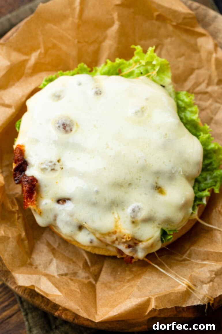 A close-up shot of a perfectly grilled turkey burger patty, crowned with a generous slice of melted Havarti cheese, resting on the grill. The rich, golden-brown patty and glistening cheese promise a juicy, flavorful bite.
