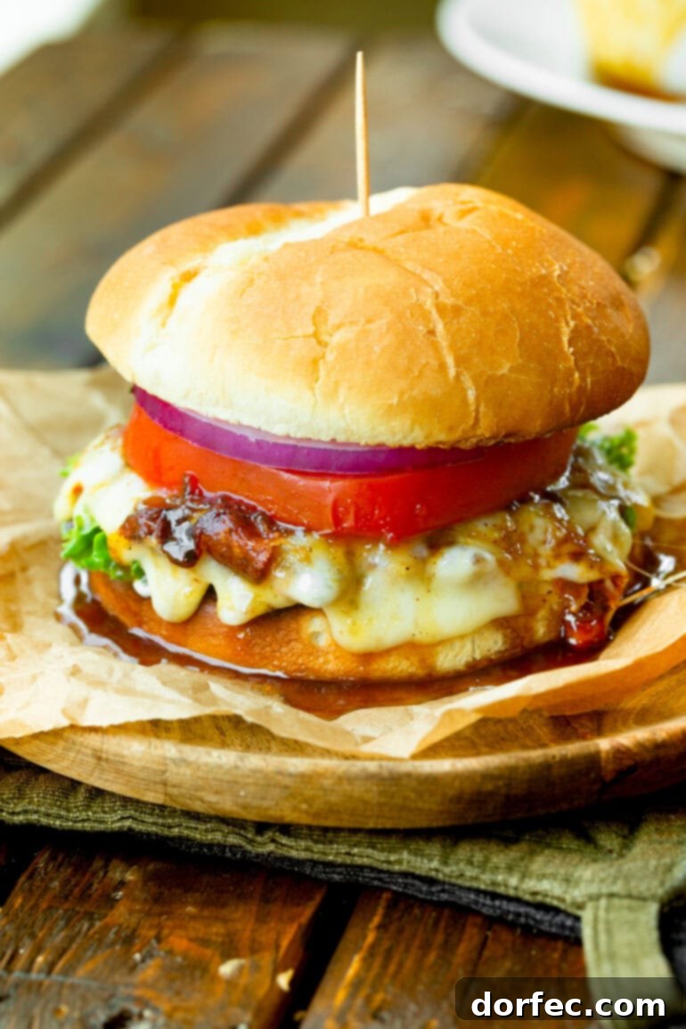 A vibrant, fully assembled pineapple jalapeno turkey burger, featuring a juicy turkey patty, melted Havarti, fresh tomato, crisp red onion, and generous drizzles of the sweet and spicy sauce cascading down its sides.
