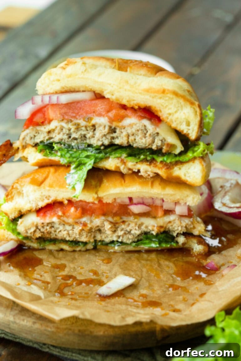 A stunning cross-section view of a pineapple jalapeno turkey burger, revealing the tender, seasoned turkey patty, generously melted Havarti cheese, crisp green lettuce, vibrant red tomato, and thinly sliced red onion on a toasted brioche bun.