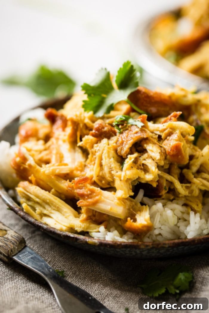 A metal, vintage bowl filled with white long grain rice and shredded chicken with a simple honey curry sauce made in an instant pot with cilantro on top. easy instant pot honey chicken