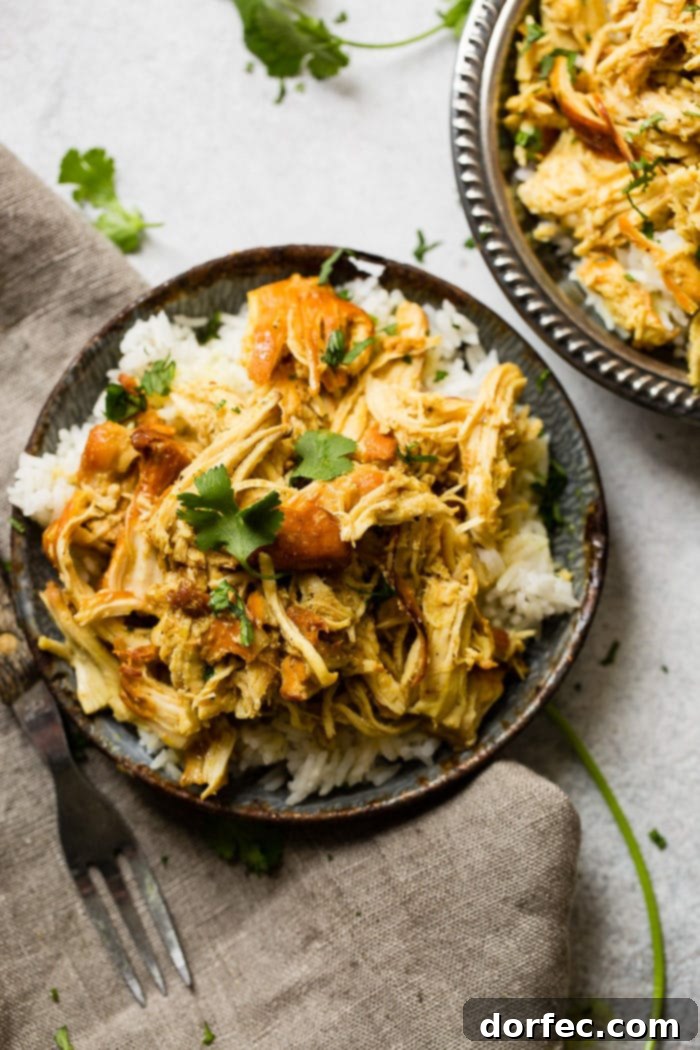 A metal, vintage bowl filled with white long grain rice and shredded chicken with a simple honey curry sauce made in an instant pot with cilantro on top. easy instant pot honey chicken