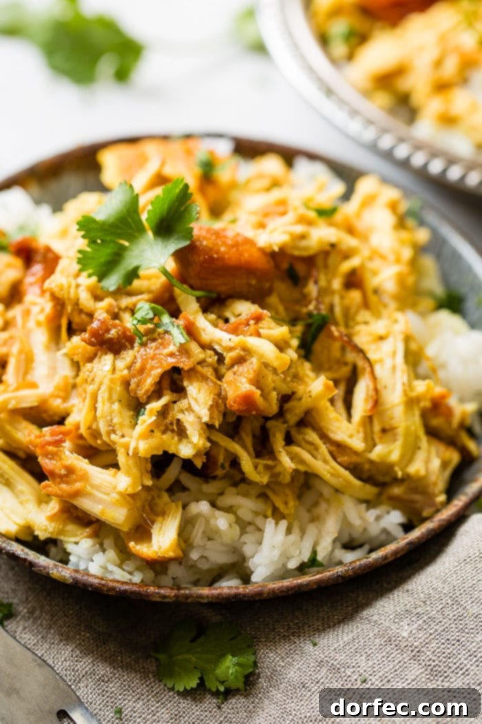 A metal, vintage bowl filled with white long grain rice and shredded chicken with a simple honey curry sauce made in an instant pot with cilantro on top. easy instant pot honey chicken
