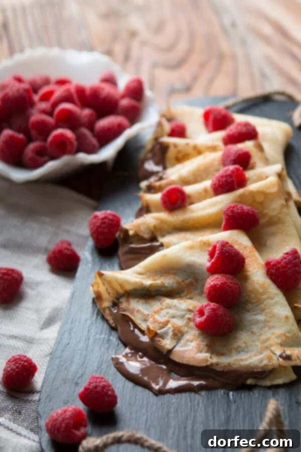 Nutella Crepes French breakfast, hazelnut, raspberry A stack of perfectly cooked Nutella Crepes ready to be served, topped with a dollop of fresh cream and berries