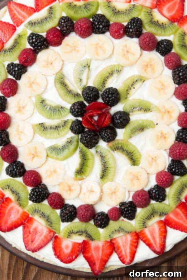 Delicious fruit pizza with a soft sugar cookie crust, topped with creamy cream cheese frosting and fresh berries.
