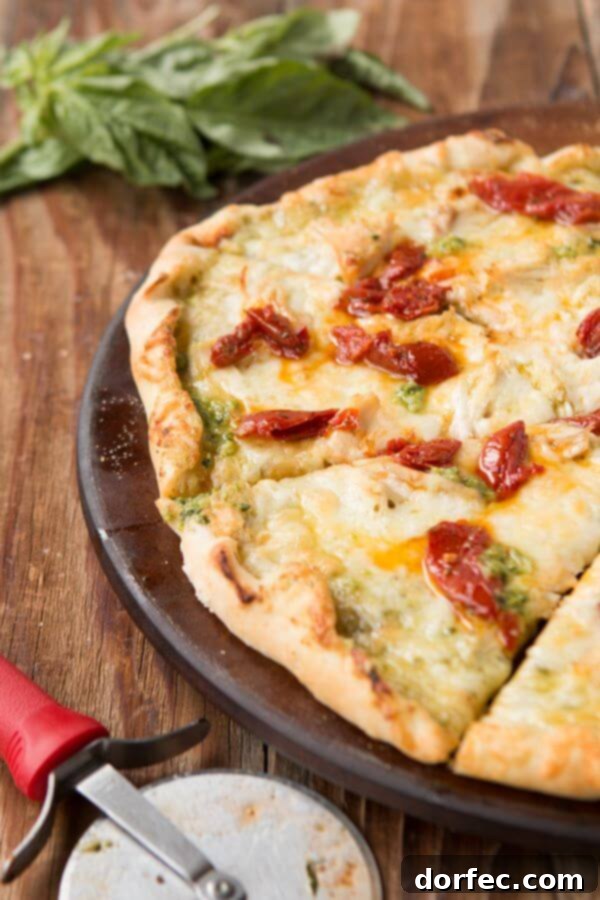 Close-up of creamy pesto chicken pizza slice with melted cheese