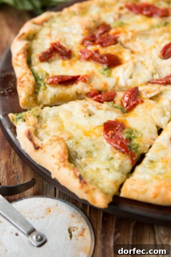 Homemade thin crust pizza with creamy pesto, chicken, and sun-dried tomatoes