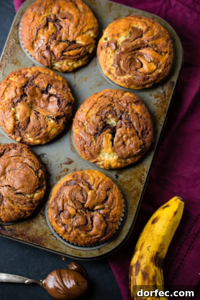 A jumbo muffin tin filled with unbaked Nutella banana muffin batter, ready for the oven, showcasing the generous portion sizes.