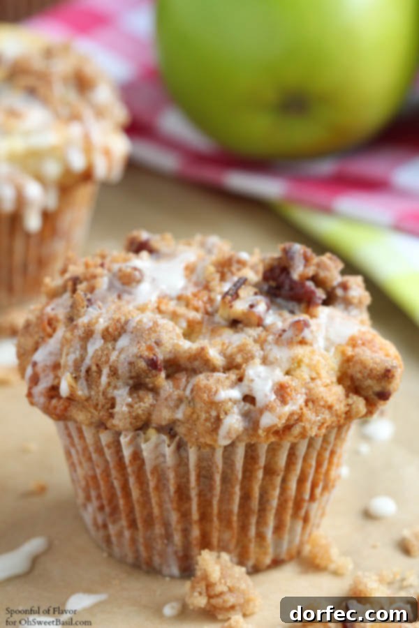 Delicious Apple Coffee Cake Muffins with a streusel topping, displayed on a rustic wooden surface, inviting viewers to try this comforting baked treat from Oh Sweet Basil.