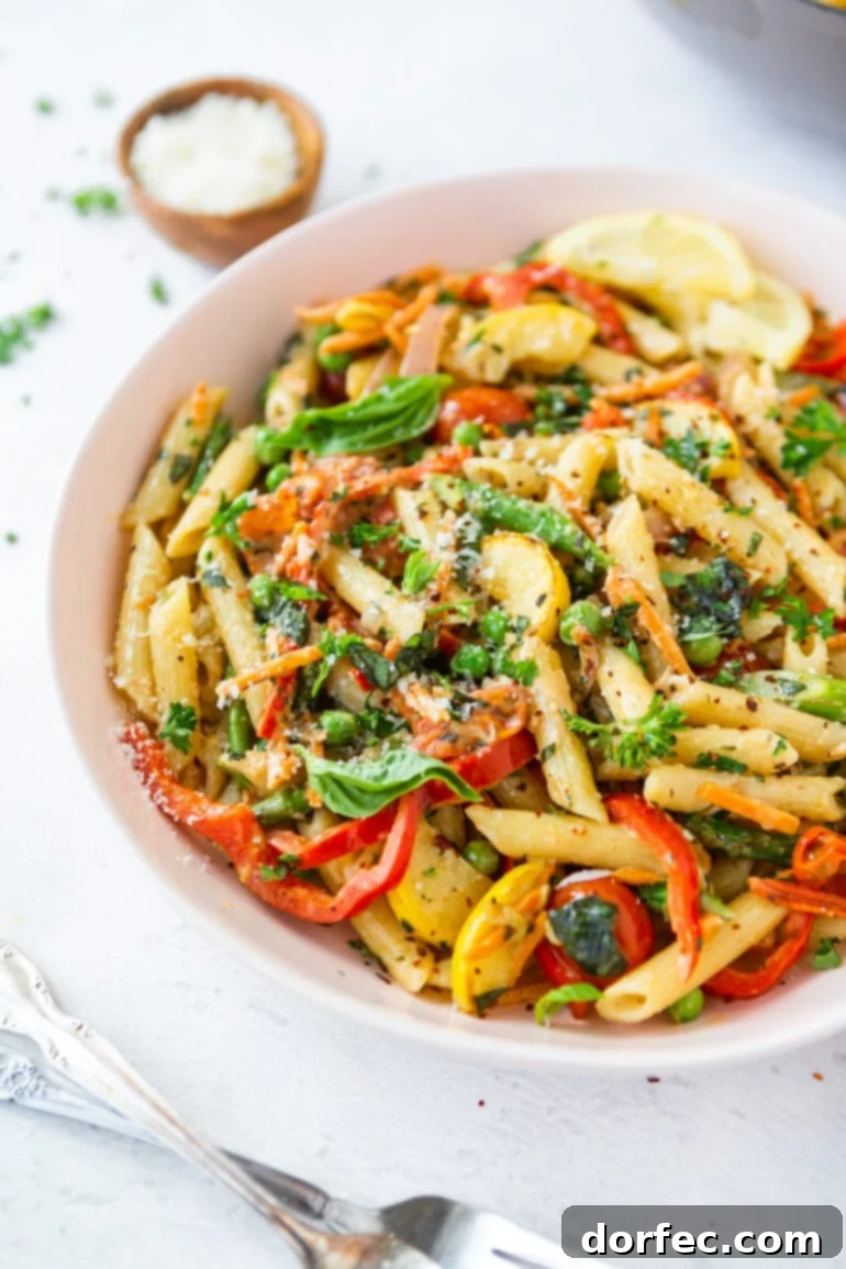 Vibrant Spring Pasta Primavera Recipe 6 A close-up view of a bowl of Pasta Primavera, featuring penne pasta, vibrant slices of red bell peppers, delicate yellow squash, red onions, and fresh herbs, ready for a delightful meal.