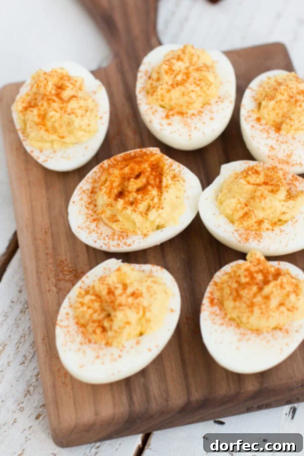 The Ultimate Creamy Deviled Eggs 3 Seven of the best Deviled Eggs on a wooden platter on top of a white wooden table.