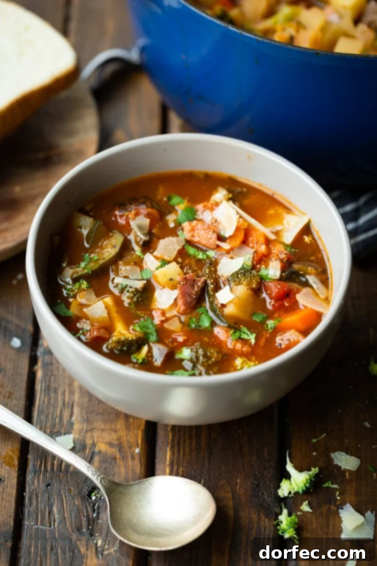 a photo of a bowl of hearty ham and vegetable soup sitting on a wooden table
