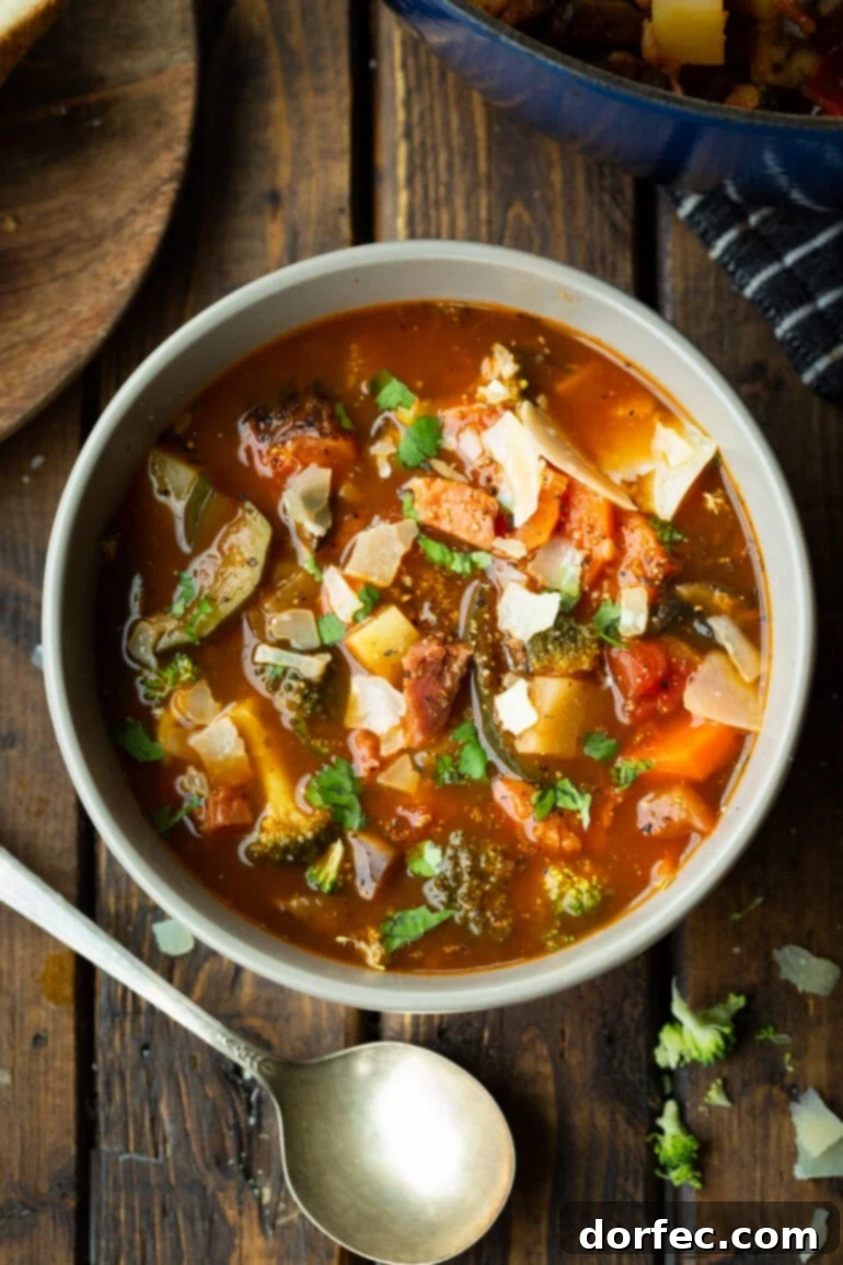 a photo taken over the top of a bowl full of ham and vegetable soup loaded with carrots, potatoes, mushrooms, broccoli and large chunks of ham.