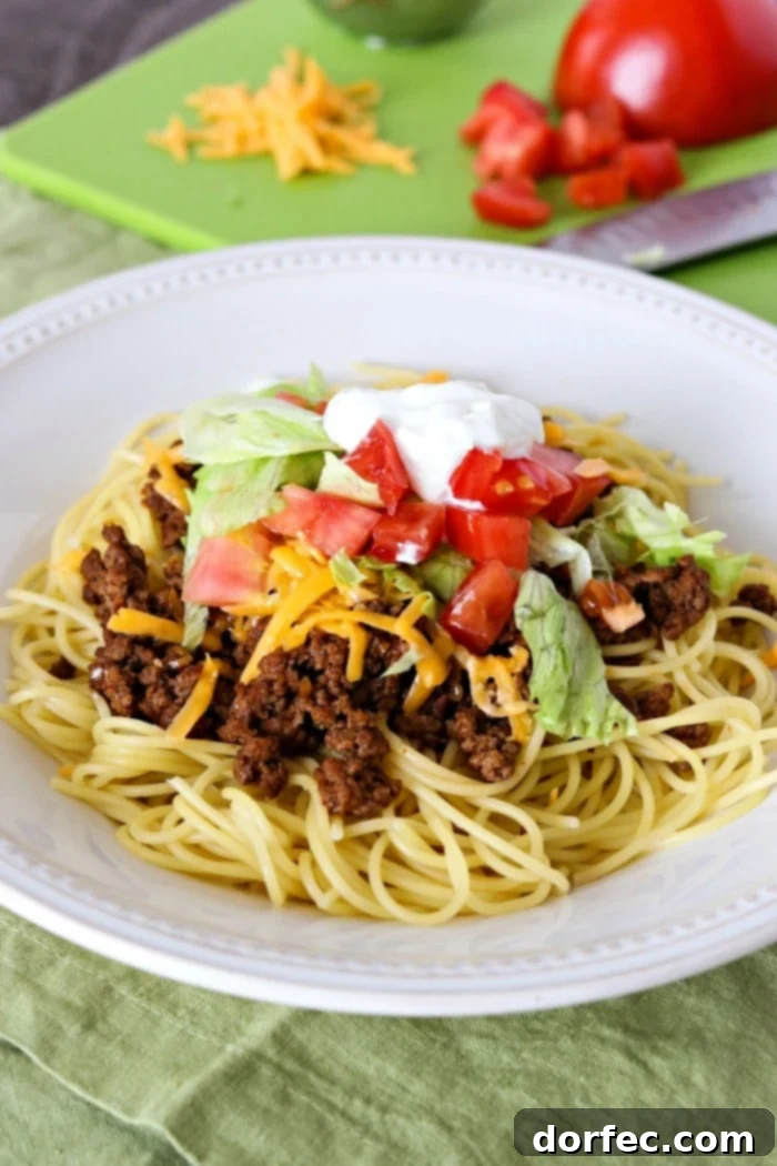 A hearty bowl of Taco Spaghetti, combining the best of Italian pasta with zesty Mexican taco seasonings and ground meat, garnished with cheese and fresh cilantro.