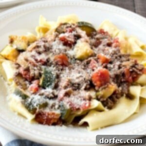 A bowl of easy beef ragu and pasta with grated parmesan cheese as garnish