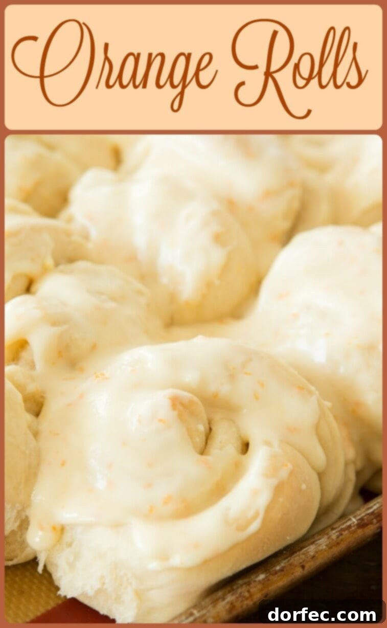 Close-up of fluffy orange rolls with a rich glaze, showing their soft texture and vibrant color.