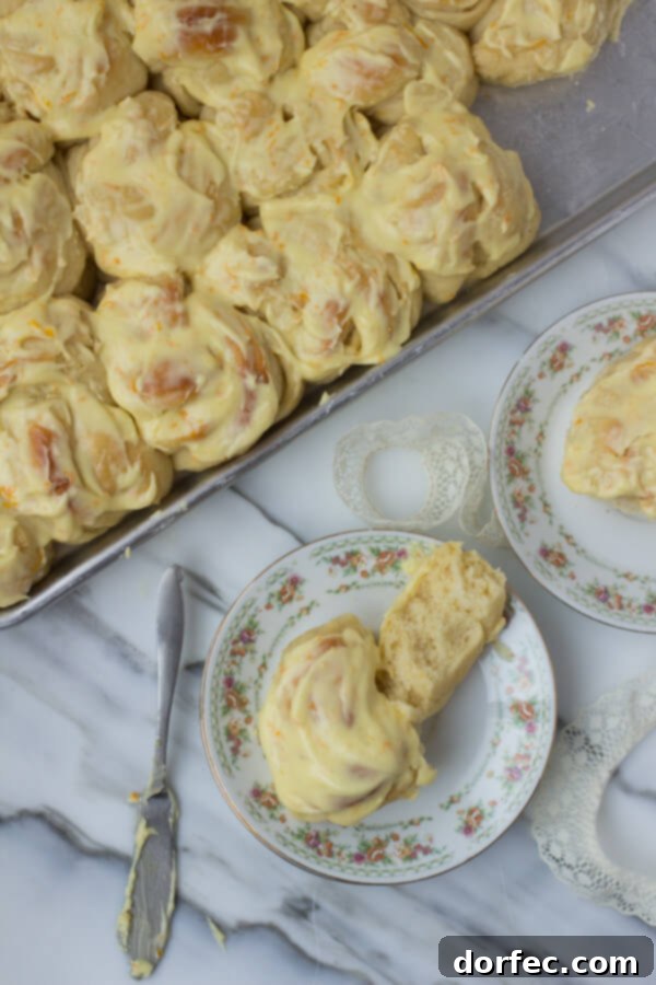 A close-up view of a plate of beautifully glazed orange rolls, showcasing their soft interior and sweet citrus topping.
