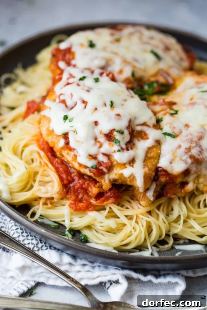 Speedy Chicken Parm Perfection 2 A dark grey platter filled with angel hair pasta, a little marinara tomato sauce, breaded chicken with marinara and melted mozzarella cheese and a sprinkle of chopped Italian flat leaf parsley. Quick and Easy shortcut chicken parmesan.