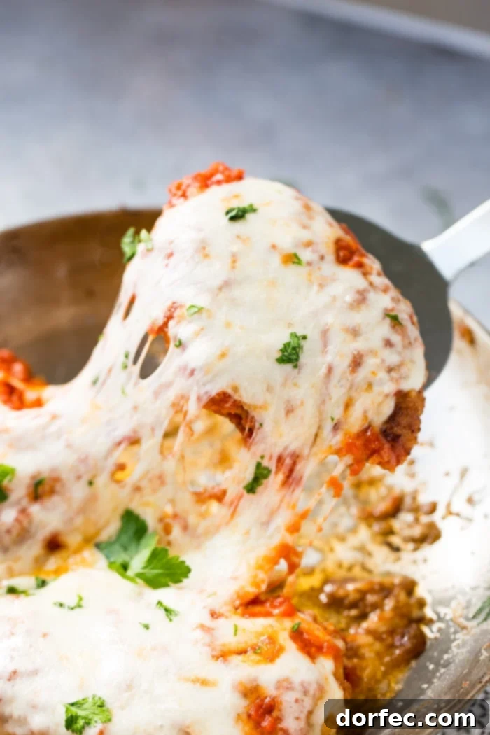 Speedy Chicken Parm Perfection 3 A skillet with breaded quick and easy shortcut chicken parmesan with gooey cheese being removed from a pan with a spatula.