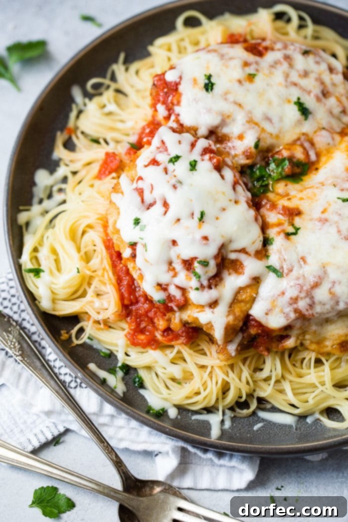 Speedy Chicken Parm Perfection 4 A dark grey platter filled with angel hair pasta, a little marinara tomato sauce, breaded chicken with marinara and melted mozzarella cheese and a sprinkle of chopped Italian flat leaf parsley. Quick and Easy shortcut chicken parmesan.