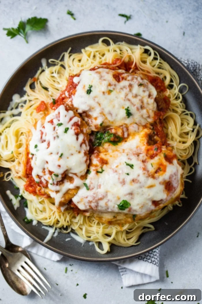Speedy Chicken Parm Perfection 5 A dark grey platter filled with angel hair pasta, a little marinara tomato sauce, breaded chicken with marinara and melted mozzarella cheese and a sprinkle of chopped Italian flat leaf parsley. Quick and Easy shortcut chicken parmesan.