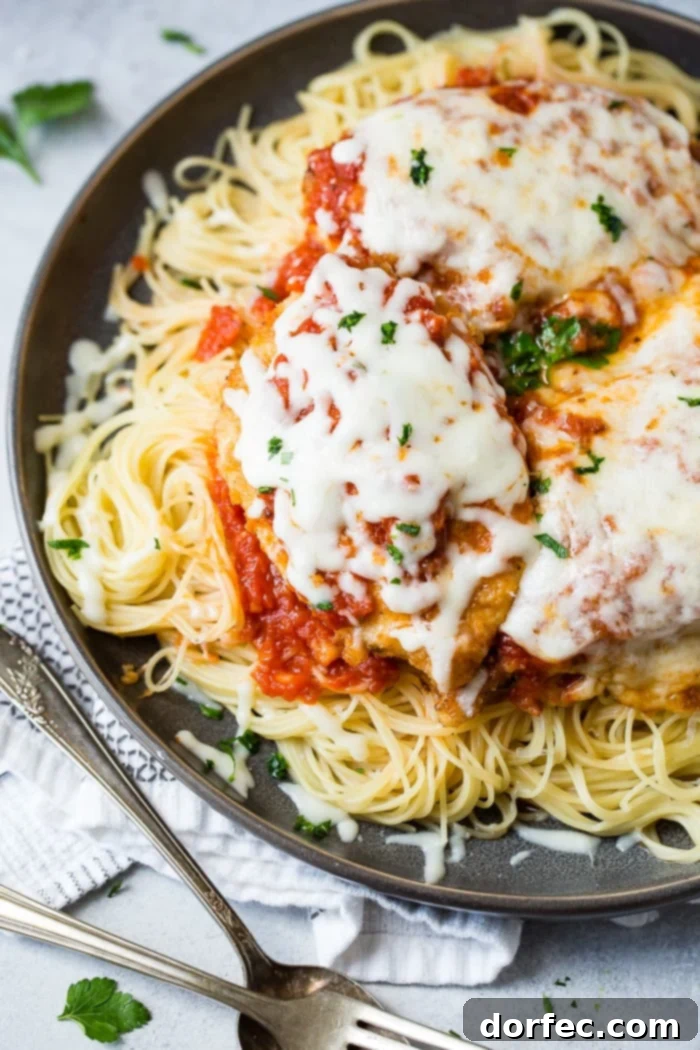 Speedy Chicken Parm Perfection 6 A dark grey platter filled with angel hair pasta, a little marinara tomato sauce, breaded chicken with marinara and melted mozzarella cheese and a sprinkle of chopped Italian flat leaf parsley. Quick and Easy shortcut chicken parmesan.