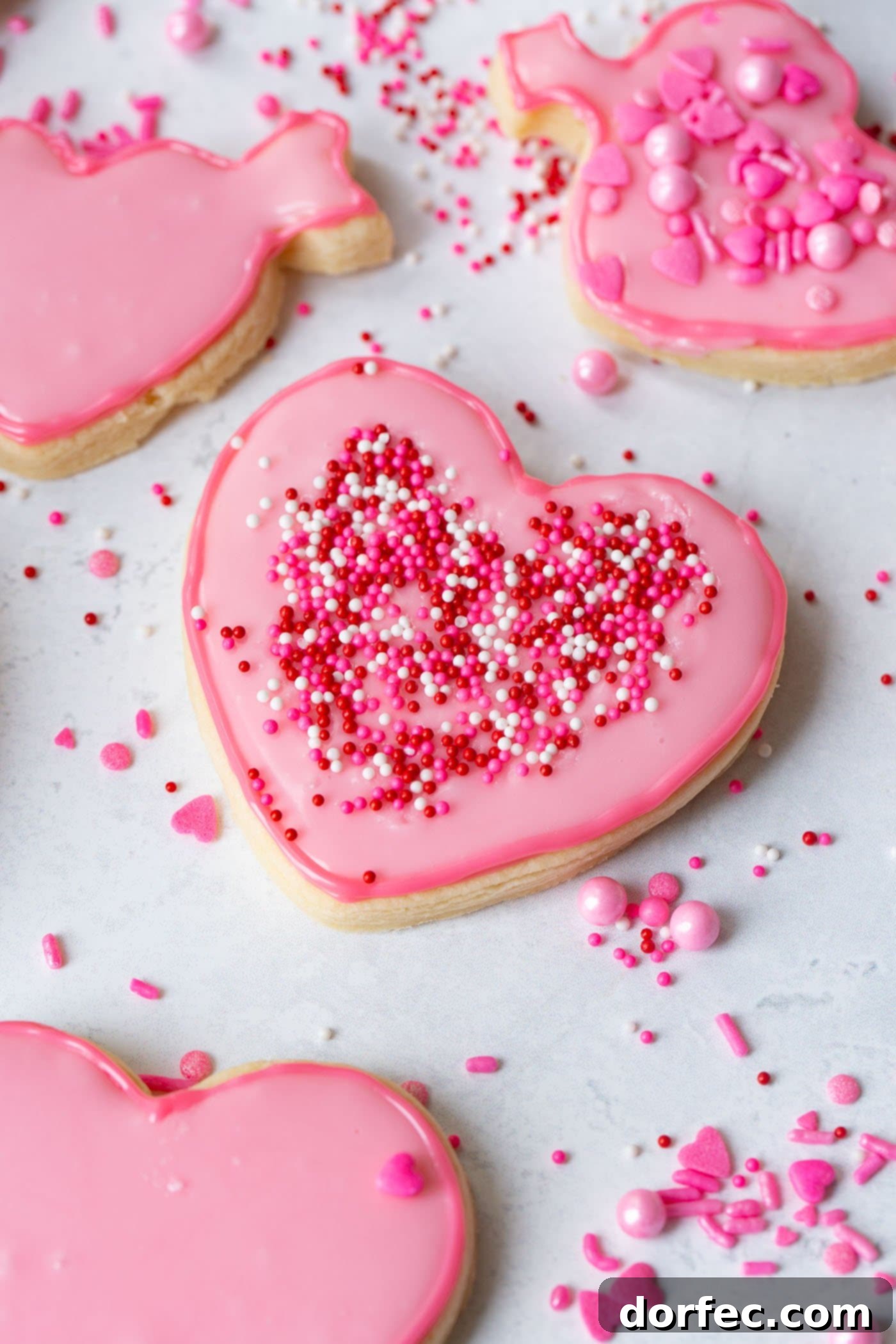 Classic Sugar Cookies 6 A single beautifully decorated pink heart-shaped sugar cookie with colorful sprinkles, ready to be enjoyed.