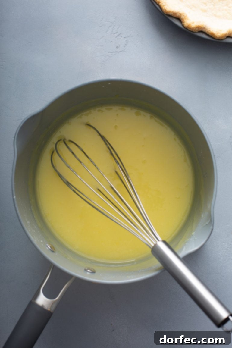Family Recipe Lemon Meringue Pie 7 A picture of a sauce pan with lemon pie filling. A whisk is in the pan.