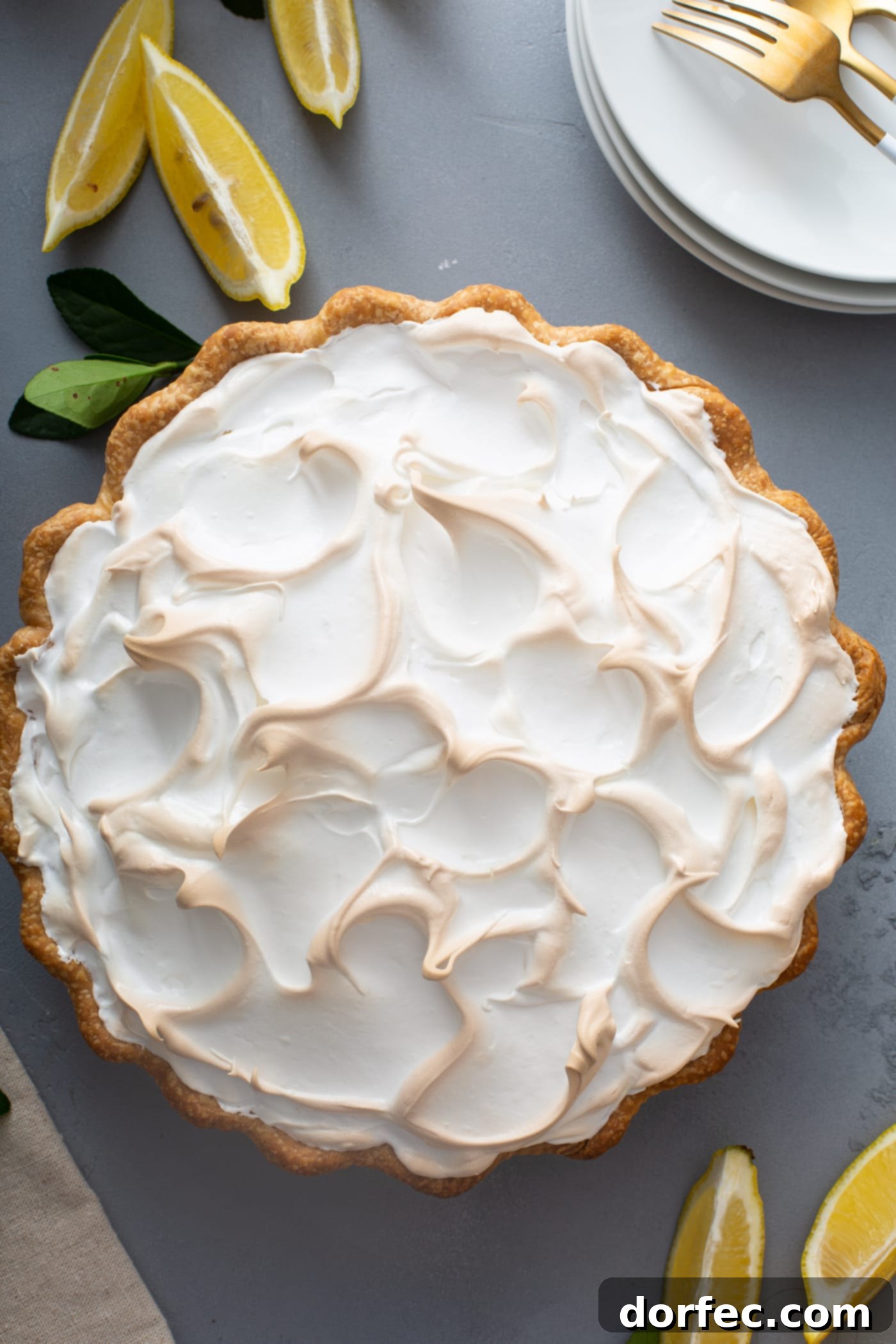 Mom's Lemon Meringue Pie A top view of a lemon meringue pie with fluffy toasted meringue on top. There are a few lemon wedges next to the pie.