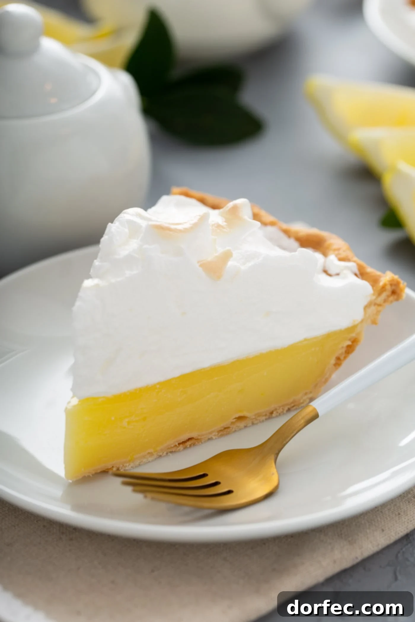 Mom's Lemon Meringue Pie A slice of lemon meringue pie on a white dessert plate. A fork is next to the pie, and one bite has been taken from the slice.