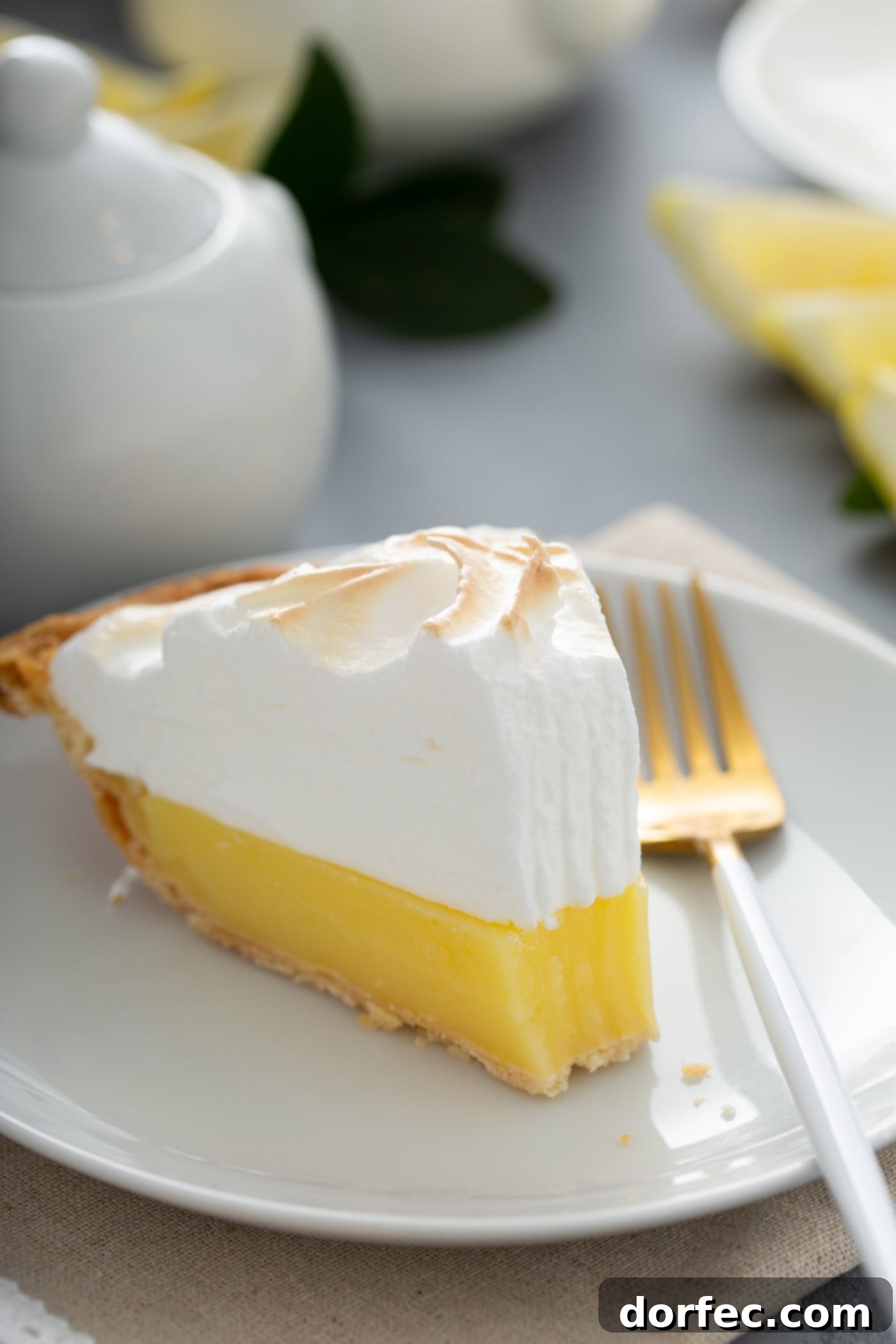 Mom's Lemon Meringue Pie A slice of lemon meringue pie on a white dessert plate. A fork is next to the pie, and one bite has been taken from the slice.