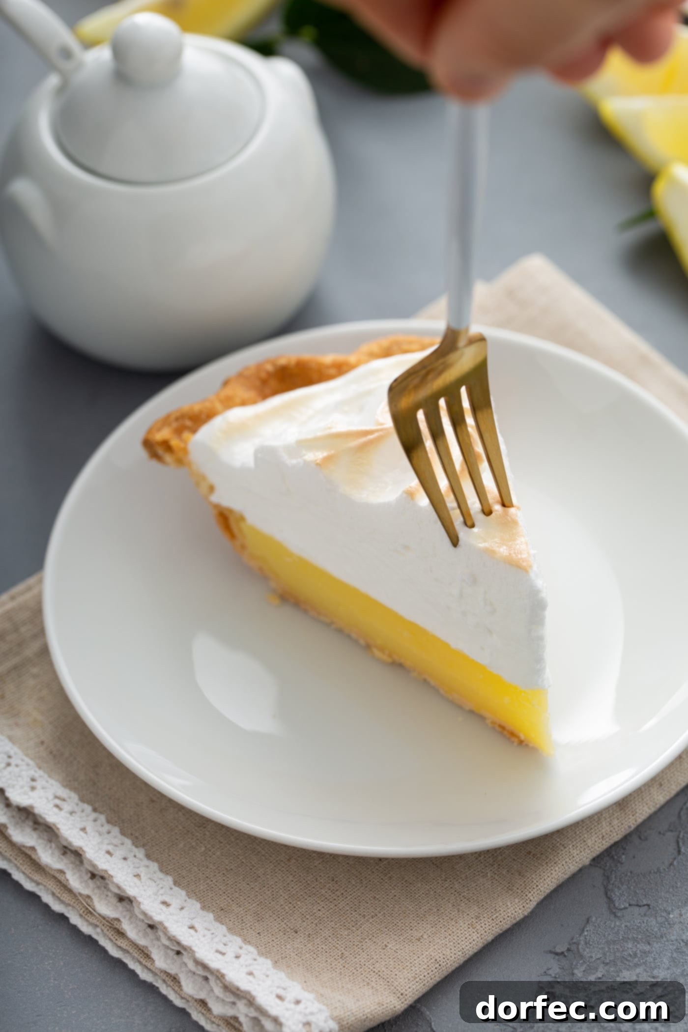 Mom's Lemon Meringue Pie A piece of lemon meringue pie. A fork is piercing the tip of the slice.