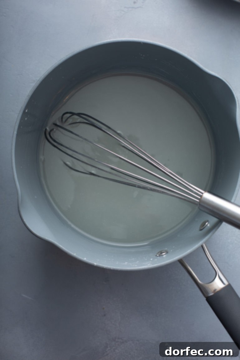 Family Recipe Lemon Meringue Pie 4 A saucepan with water and sugar and a whisk.