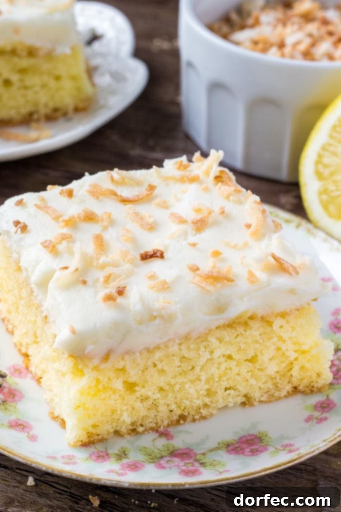 A delicate slice of Lemon Coconut Cake presented on a beautiful floral plate, highlighting its inviting texture and frosting.