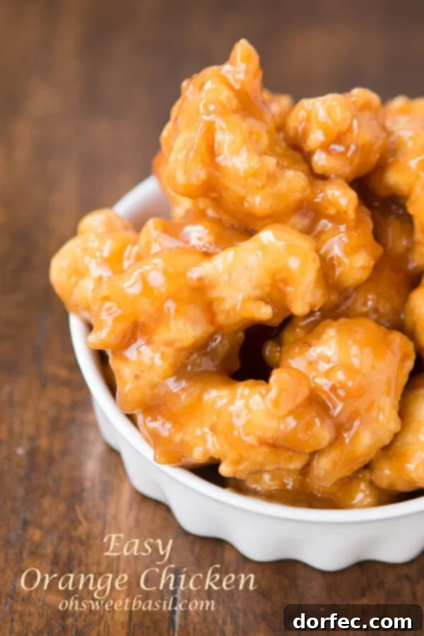 Asian Orange Chicken in a white bowl on a wooden table.