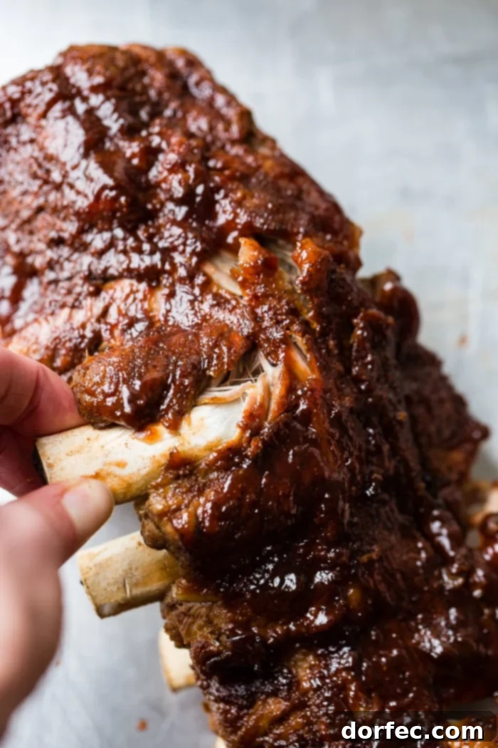 A cookie sheet with a pile of smoky bbq instant pot ribs slathered with bbq sauce and falling right off of the bone