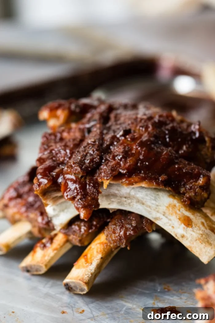A cookie sheet with a pile of smoky bbq instant pot ribs slathered with bbq sauce and falling right off of the bone