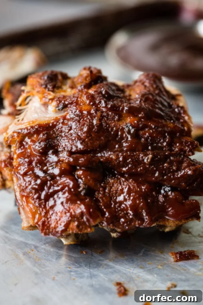 A cookie sheet with a pile of smoky bbq instant pot ribs slathered with bbq sauce and falling right off of the bone