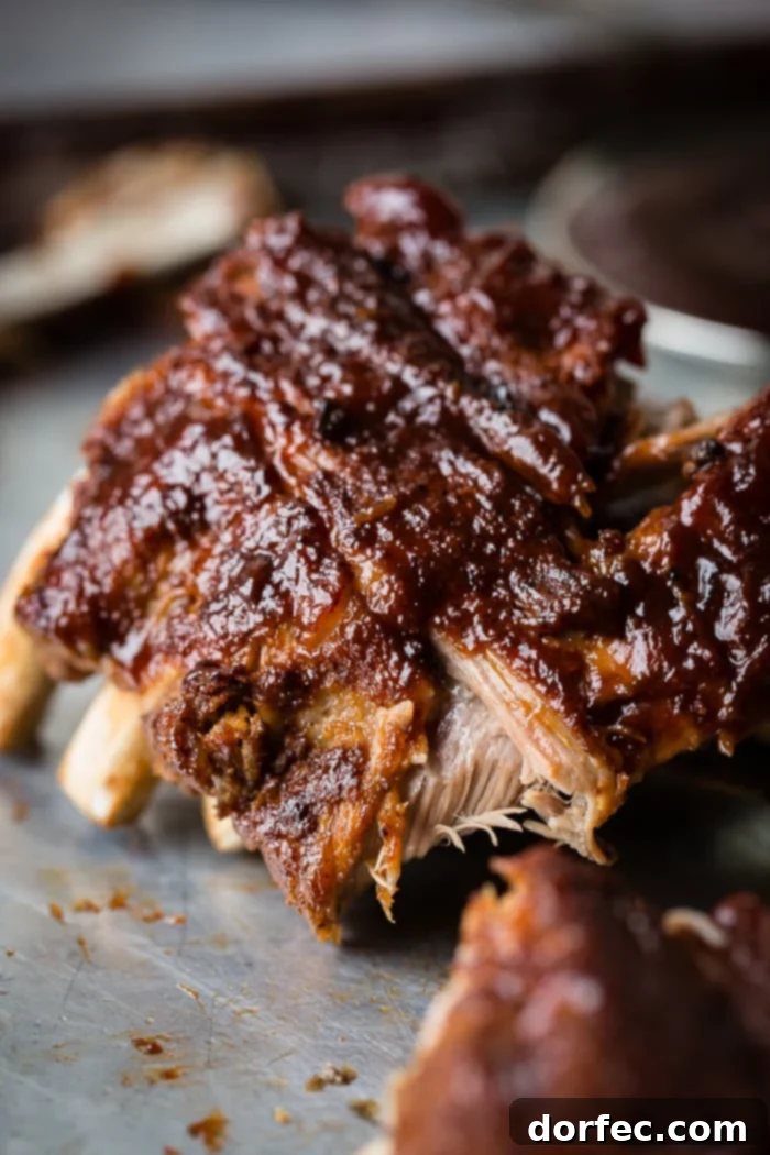 A cookie sheet with a pile of smoky bbq instant pot ribs slathered with bbq sauce and falling right off of the bone