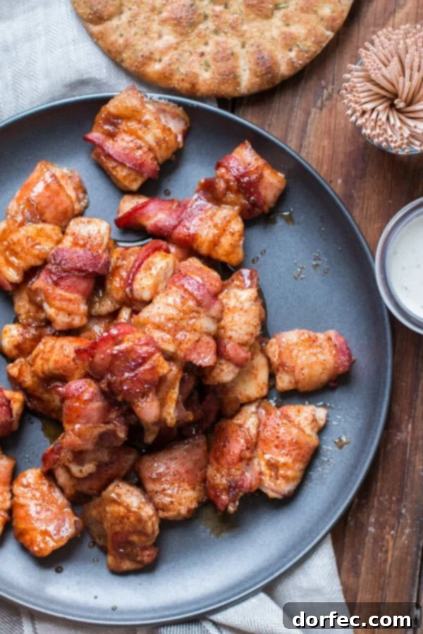 Pile of Brown Sugar Bacon Chicken Appetizers overhead view of a pile of golden brown brown sugar bacon chicken bites on a gray plate, ready to serve