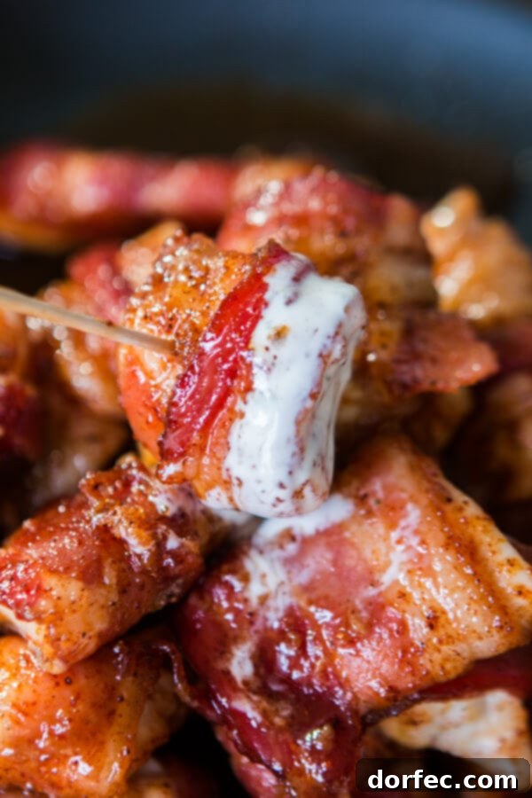 Single Bacon-Wrapped Chicken Bite on a Toothpick close up of a single piece of bacon wrapped chicken on a toothpick, highlighting its crispy texture