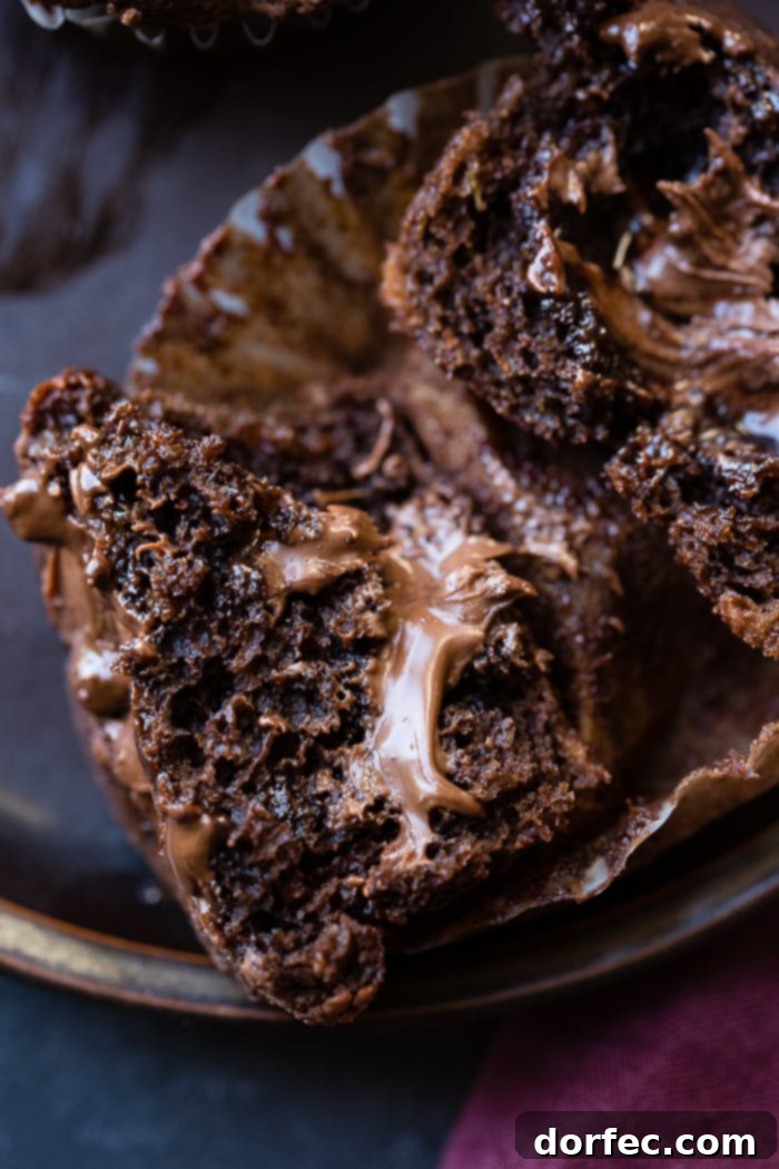 A Nutella stuffed double chocolate banana muffin cut in half, revealing the creamy center
