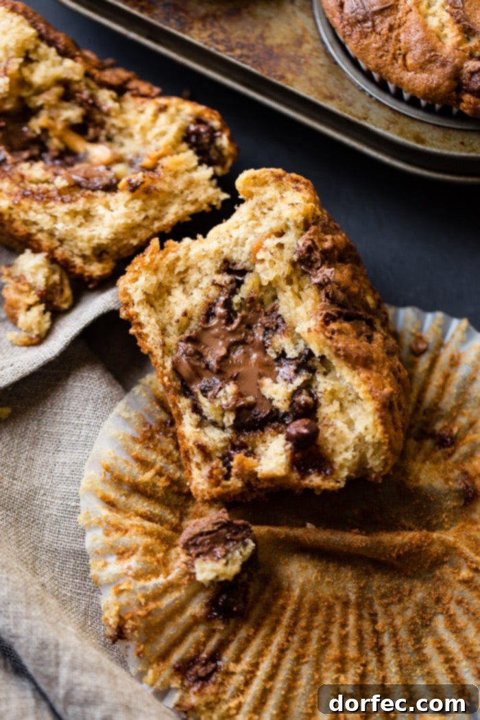 Nutella Surprise Peanut Butter Banana Muffins 5 A sliced open Nutella stuffed peanut butter banana muffin, revealing the gooey Nutella center, sitting on an open muffin liner.