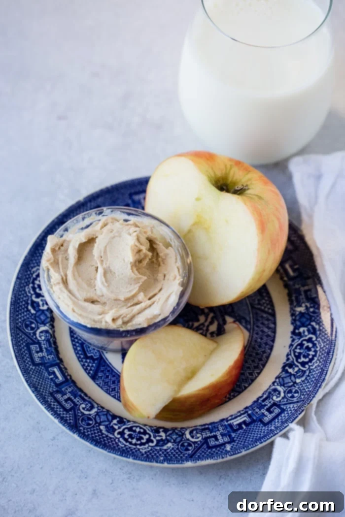 Another view of the blue dish with sliced apples and a small bowl of healthy peanut butter Greek yogurt dip, emphasizing its appeal as a wholesome, dessert-like snack.