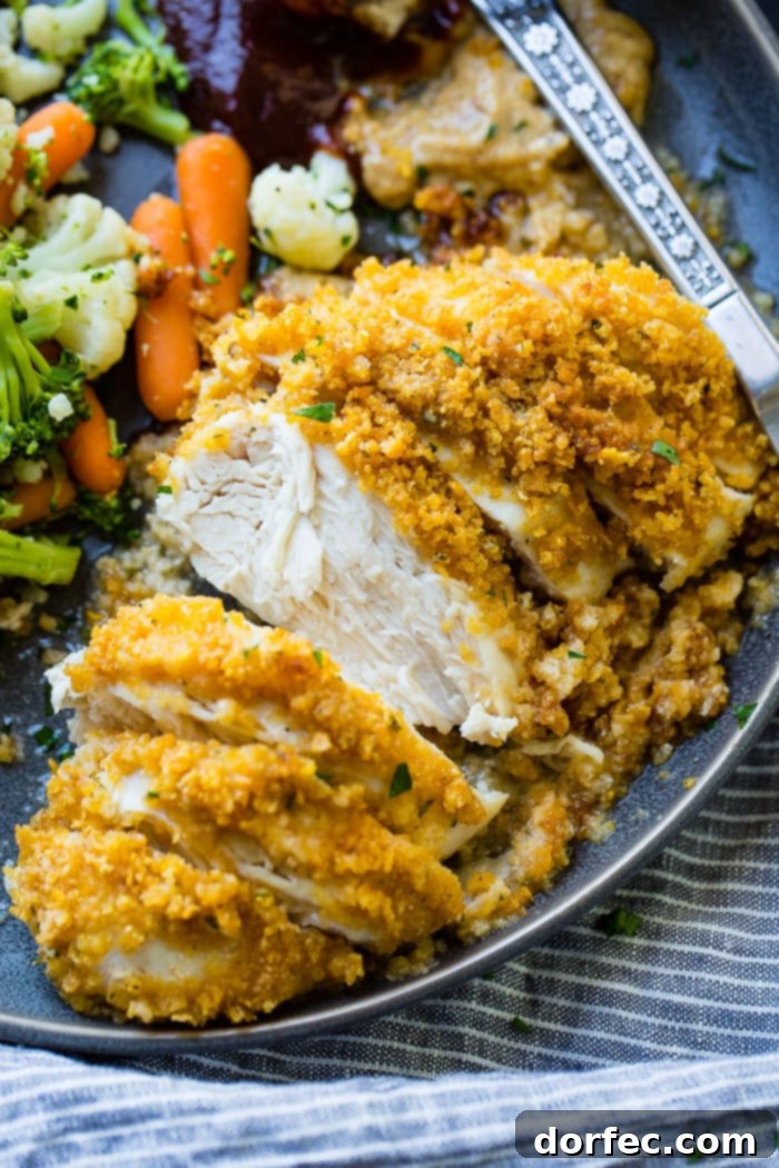 a grey plate full of steamed veggies and golden, baked quick and easy cornflake chicken recipe which has been sliced into pieces of chicken