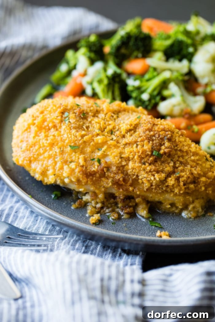 a grey plate full of steamed veggies and golden, baked quick and easy cornflake chicken recipe which has been sliced into pieces of chicken