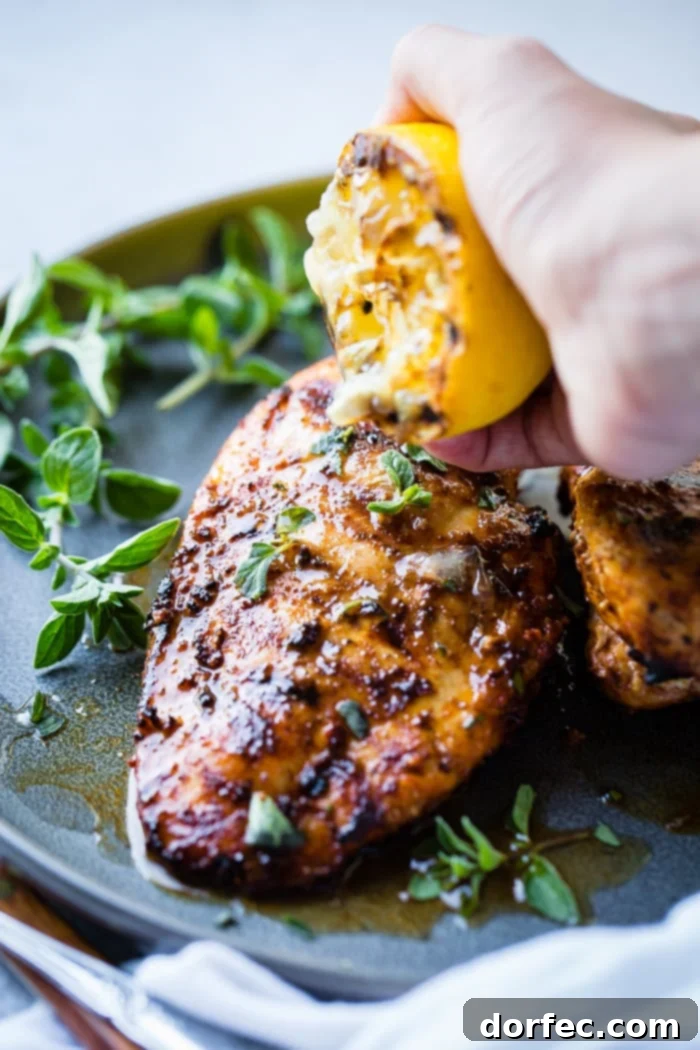 Speedy Oregano Grilled Chicken 6 A grey plate with a sliced quick grilled chicken with oregano with oregano and a grilled lemon being squeezed over the meat