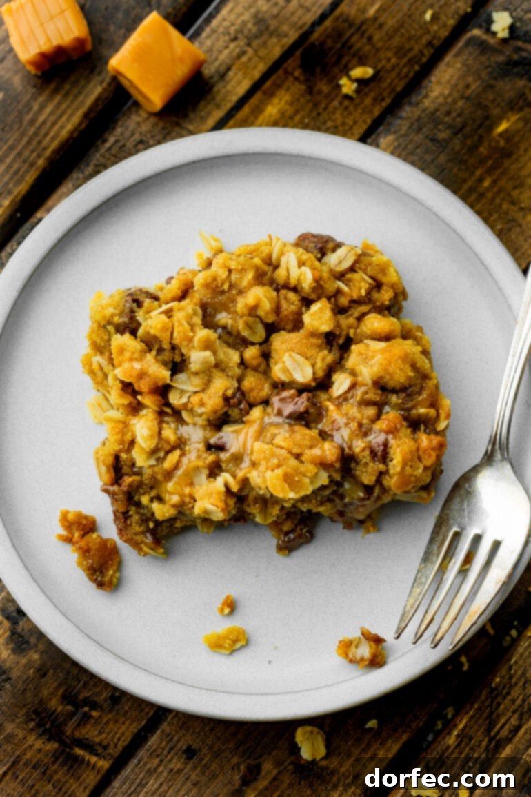 A top-down photo of a Carmelita bar, showcasing its golden oat crumble and the luscious, oozing caramel and chocolate beneath.