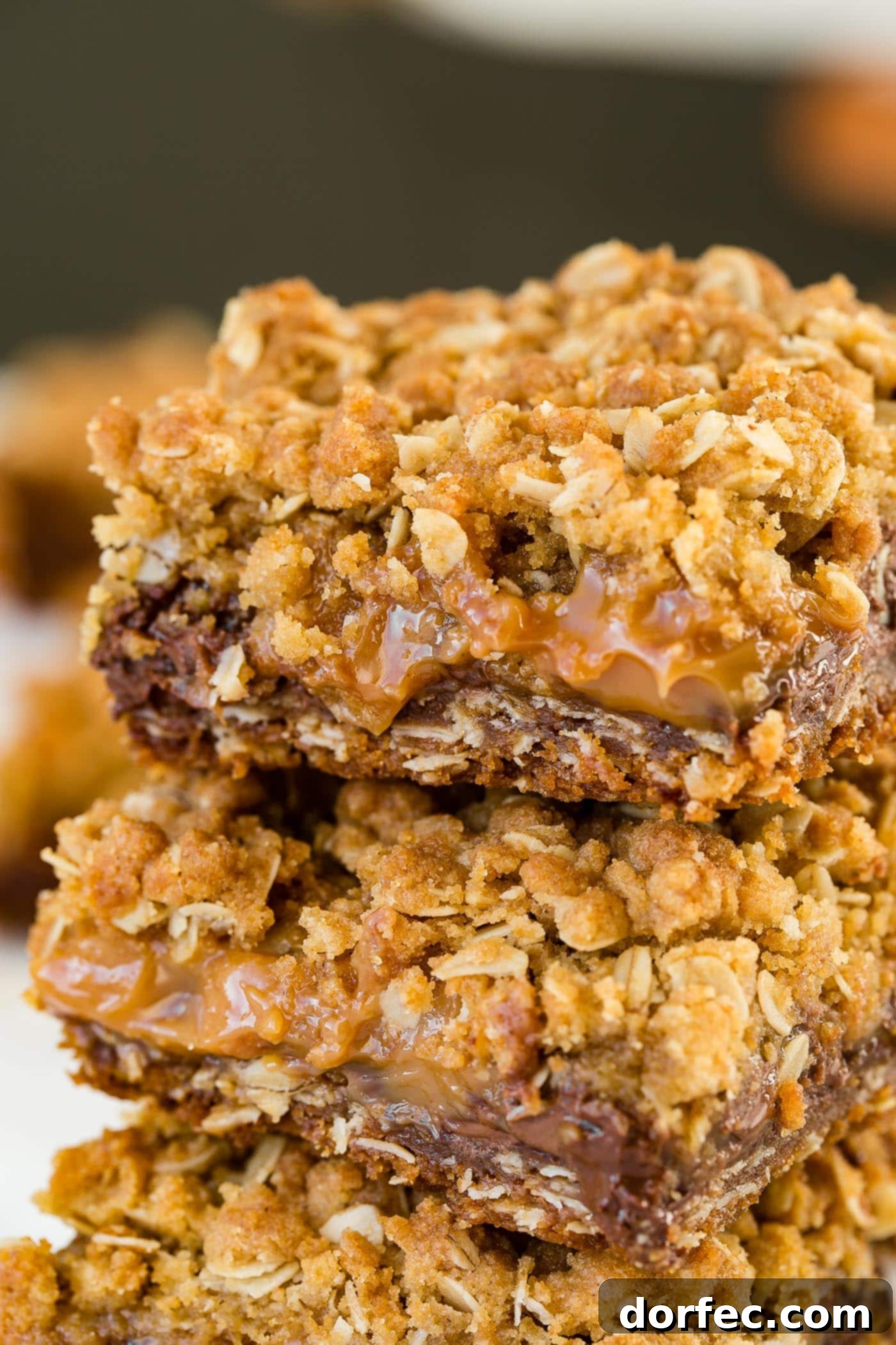 A photo showing a stack of three Carmelita bars, with the rich layers of oat, chocolate, and caramel clearly visible and enticing.